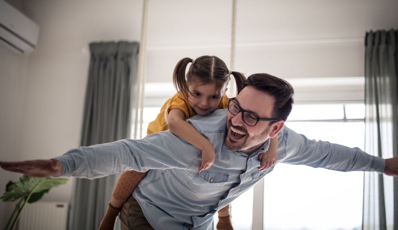 Un papa souriant porte sa fille sur son dos